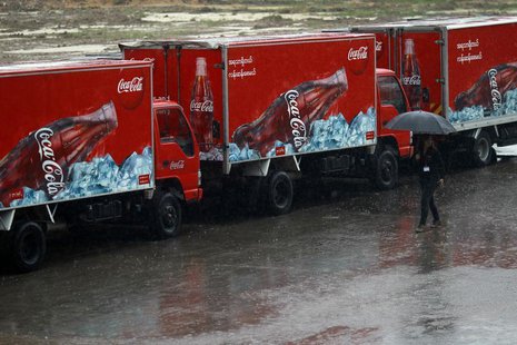 A woman walks near Coca-Cola vehicles during rainfall in Yangon June 4, 2013. REUTERS/Soe Zeya Tun A woman walks near Coca-Cola vehicles during rainfall in Yangon June 4, 2013. REUTERS/Soe Zeya Tun