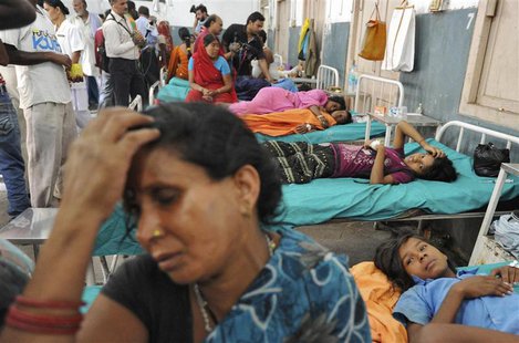 Asha Devi holds her head while sitting next to her sick daughter Savita (R) who consumed spurious meals at a school on Tuesday, at a hospita Asha Devi holds her head while sitting next to her sick daughter Savita (R) who consumed spurious meals at a school on Tuesday, at a hospita
