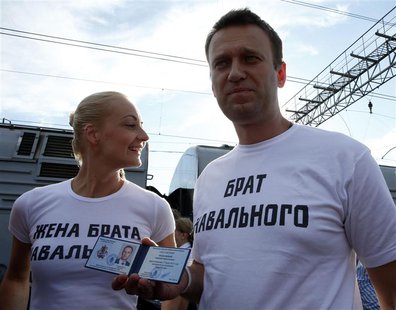 Anti-corruption blogger Alexei Navalny holds his Moscow mayor candidate registration certificate as his wife Yulia looks on before leaving f Anti-corruption blogger Alexei Navalny holds his Moscow mayor candidate registration certificate as his wife Yulia looks on before leaving f
