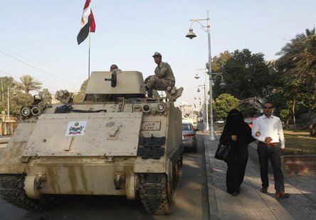 A couple walks past an Egyptian soldier keeping watch from atop a military vehicle in front of the presidential palace in Cairo July 14, 201 A couple walks past an Egyptian soldier keeping watch from atop a military vehicle in front of the presidential palace in Cairo July 14, 201