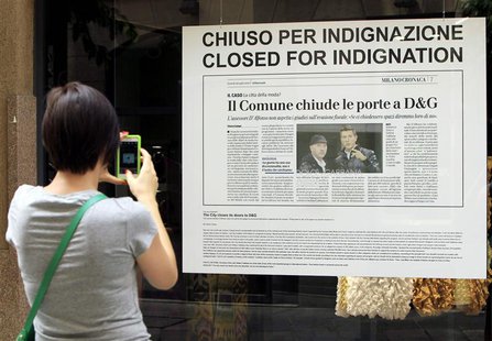 A girl takes a picture of the windows of a Dolce&Gabbana closed store, displaying a newspaper article as a protest in downtown Milan July 19 A girl takes a picture of the windows of a Dolce&Gabbana closed store, displaying a newspaper article as a protest in downtown Milan July 19