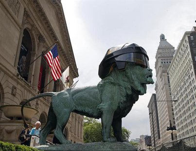 A woman walks past one of the bronze lion statues in front of the Art Institute of Chicago that was fitted with an oversized hockey helmet i A woman walks past one of the bronze lion statues in front of the Art Institute of Chicago that was fitted with an oversized hockey helmet i