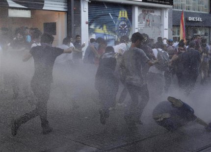 Anti-government protesters take cover as riot police use water cannon to disperse them at Taksim square in central Istanbul July 20, 2013. R Anti-government protesters take cover as riot police use water cannon to disperse them at Taksim square in central Istanbul July 20, 2013. R