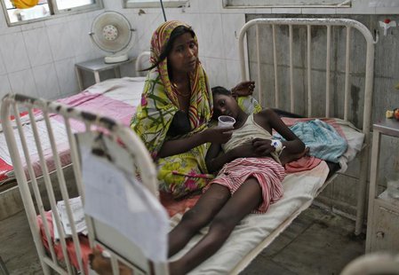A sick boy lies on his mother's lap inside a hospital after he consumed contaminated meals given to children at a school on Tuesday, in the A sick boy lies on his mother's lap inside a hospital after he consumed contaminated meals given to children at a school on Tuesday, in the