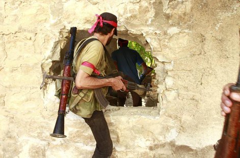 Free Syrian Army fighters move through a hole in a wall in the northern town of Khan al-Assal, after seizing it July 22, 2013. REUTERS/Hamid Free Syrian Army fighters move through a hole in a wall in the northern town of Khan al-Assal, after seizing it July 22, 2013. REUTERS/Hamid