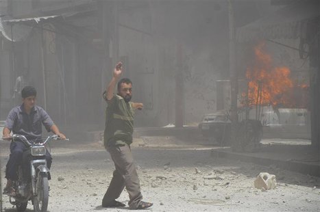 A man points towards a burning car, caused by what activists said was shelling by forces loyal to Syria's President Bashar al-Assad, in the A man points towards a burning car, caused by what activists said was shelling by forces loyal to Syria's President Bashar al-Assad, in the