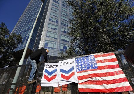 A demonstrator climbs onto a police fence covered with a U.S. flag and Chevron signs by other demonstrators, during a protest against the Ar A demonstrator climbs onto a police fence covered with a U.S. flag and Chevron signs by other demonstrators, during a protest against the Ar
