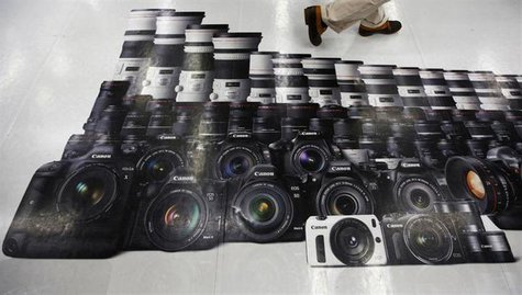 A man walks on an advertisement of Canon digital cameras at an electronics retail store in Tokyo July 24, 2013.REUTERS/Issei Kato A man walks on an advertisement of Canon digital cameras at an electronics retail store in Tokyo July 24, 2013.REUTERS/Issei Kato
