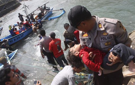 A police officer carries an unconscious child who was on the boat that capsized late on Tuesday after hitting a reef off the coast of Sukapu A police officer carries an unconscious child who was on the boat that capsized late on Tuesday after hitting a reef off the coast of Sukapu