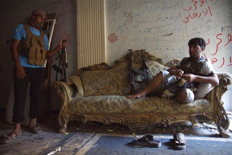 A Free Syrian Army fighter rests on a sofa as a fellow fighter stands near him inside a house in Deir al-Zor July 23, 2013. Picture taken Ju A Free Syrian Army fighter rests on a sofa as a fellow fighter stands near him inside a house in Deir al-Zor July 23, 2013. Picture taken Ju