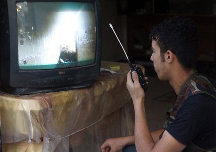 A Free Syrian Army fighter uses a walkie-talkie to talk with a fellow fighter as he watches a surveillance monitor in Deir al-Zor July 25, 2 A Free Syrian Army fighter uses a walkie-talkie to talk with a fellow fighter as he watches a surveillance monitor in Deir al-Zor July 25, 2