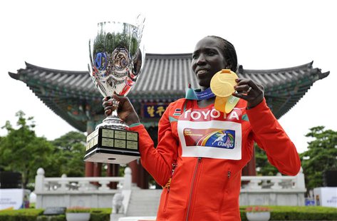 Edna Kiplagat of Kenya holds up her gold medal and the trophy presented to the winning team after the women's marathon final at the IAAF Wor Edna Kiplagat of Kenya holds up her gold medal and the trophy presented to the winning team after the women's marathon final at the IAAF Wor