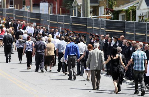 Mourners walk the perimeter of the red zone as rescue workers line the streets following a memorial service to honour the victims of the tra Mourners walk the perimeter of the red zone as rescue workers line the streets following a memorial service to honour the victims of the tra