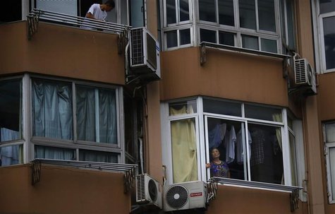 A woman stands next to her apartment window in downtown Shanghai July 26, 2013. REUTERS/Carlos Barria A woman stands next to her apartment window in downtown Shanghai July 26, 2013. REUTERS/Carlos Barria