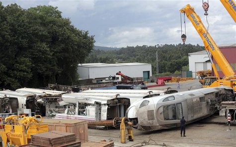A Spanish National police officer stands next to wrecked parts of a train at a warehouse in Escravitude, 20 km (12 miles) from Santiago de C A Spanish National police officer stands next to wrecked parts of a train at a warehouse in Escravitude, 20 km (12 miles) from Santiago de C