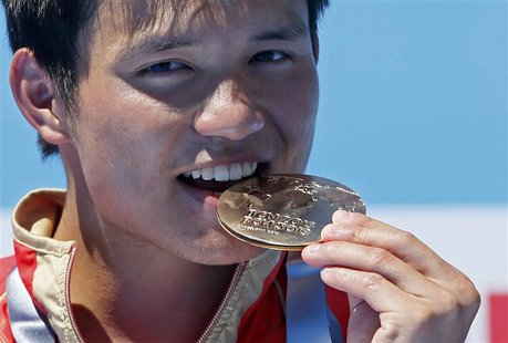 Gold medallist Qiu Bo of China bites his medal during the men's 10m platform victory ceremony at the World Swimming Championships at the Mon Gold medallist Qiu Bo of China bites his medal during the men's 10m platform victory ceremony at the World Swimming Championships at the Mon