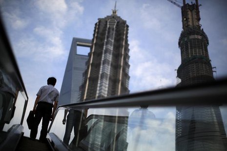 A man rides an escalator near Shanghai Tower (R, under construction), Jin Mao Tower (C) and the Shanghai World Financial Center (L) at the P A man rides an escalator near Shanghai Tower (R, under construction), Jin Mao Tower (C) and the Shanghai World Financial Center (L) at the P