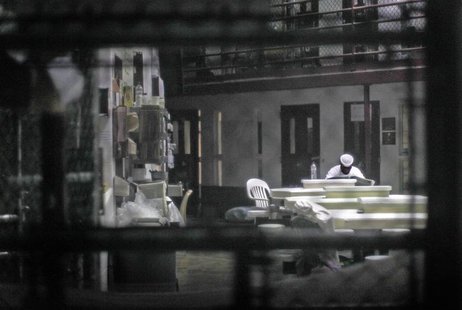 An unidentified prisoner reads a newspaper in a communal cellblock at Camp VI, a prison used to house detainees at Guantanamo Bay U.S. Naval An unidentified prisoner reads a newspaper in a communal cellblock at Camp VI, a prison used to house detainees at Guantanamo Bay U.S. Naval