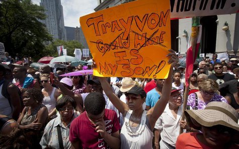 Irene Renee holds up a sign as her son Zavier bows his head while they attend a rally for Trayvon Martin in New York July 20, 2013. REUTERS/ Irene Renee holds up a sign as her son Zavier bows his head while they attend a rally for Trayvon Martin in New York July 20, 2013. REUTERS/
