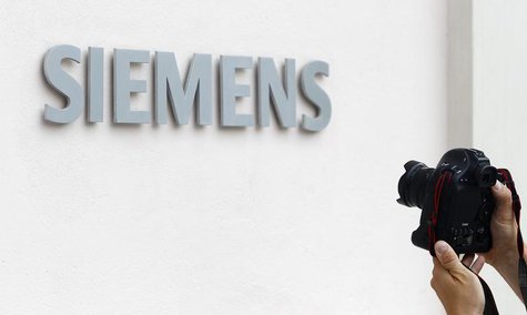 A photographer takes a picture of the Siemens logo at Germany's Siemens AG headquarter during board member meeting in Munich July 31, 2013. A photographer takes a picture of the Siemens logo at Germany's Siemens AG headquarter during board member meeting in Munich July 31, 2013.