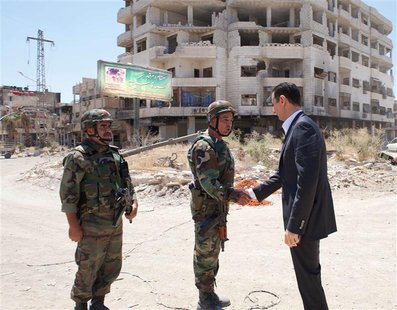 Syria's President Bashar al-Assad (R) shakes hands with a military personnel during his visit to a military site at Darya area, on the occas Syria's President Bashar al-Assad (R) shakes hands with a military personnel during his visit to a military site at Darya area, on the occas