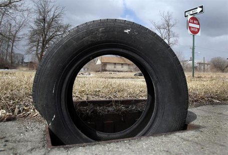 A tire sits on a storm drain as a replacement for a cast iron grate, stolen for scrap, in a neighborhood where most of the grates are missin A tire sits on a storm drain as a replacement for a cast iron grate, stolen for scrap, in a neighborhood where most of the grates are missin