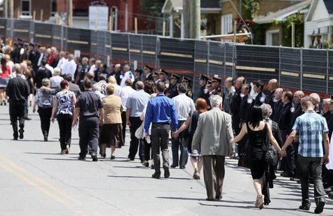 Mourners walk the perimeter of the red zone as rescue workers line the streets following a memorial service to honour the victims of the tra Mourners walk the perimeter of the red zone as rescue workers line the streets following a memorial service to honour the victims of the tra