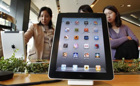 Visitors look Apple iPad 2 tablets, behind another iPad 2 on display, at a registration desk at South Korean mobile carrier KT's headquarter Visitors look Apple iPad 2 tablets, behind another iPad 2 on display, at a registration desk at South Korean mobile carrier KT's headquarter