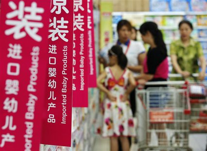 Customers talk to a sales assistant as they shop for milk powder in front of shelves displaying imported baby products at a supermarket in B Customers talk to a sales assistant as they shop for milk powder in front of shelves displaying imported baby products at a supermarket in B