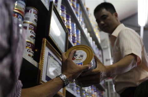 An Abbott Laboratories sales staff hands over a powder milk tin during a production recall at a milk shop outside Hanoi August 6, 2013. REUT An Abbott Laboratories sales staff hands over a powder milk tin during a production recall at a milk shop outside Hanoi August 6, 2013. REUT