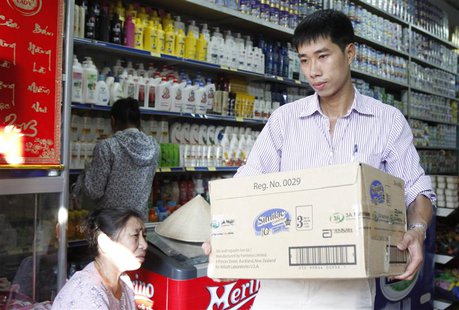 An Abbott Laboratories sales staff carries a carton of powder milk tins out of a shop during a production recall outside Hanoi August 6, 201 An Abbott Laboratories sales staff carries a carton of powder milk tins out of a shop during a production recall outside Hanoi August 6, 201