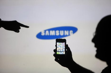 Men are silhouetted against a video screen with an Samsung logo as they pose with an Apple iPhone 4 smartphone in this photo illustration ta Men are silhouetted against a video screen with an Samsung logo as they pose with an Apple iPhone 4 smartphone in this photo illustration ta