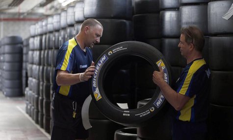 Workers hold a motorsport racing tyre stocked in the Michelin tyre company's factory in Clermont-Ferrand, central France, July 10, 2013. REU Workers hold a motorsport racing tyre stocked in the Michelin tyre company's factory in Clermont-Ferrand, central France, July 10, 2013. REU
