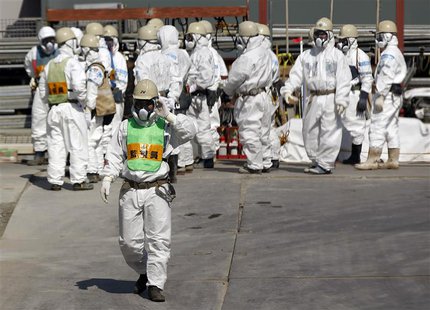 Workers wearing protective suits and masks stand next to the No.4 reactor at Tokyo Electric Power Company's (TEPCO) tsunami-crippled Fukushi Workers wearing protective suits and masks stand next to the No.4 reactor at Tokyo Electric Power Company's (TEPCO) tsunami-crippled Fukushi