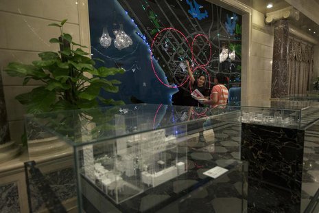 A property sales agent (L) shows a potential buyer an electronic map of the Qianhai special economic zone in Shenzhen August 16, 2013. REUTE A property sales agent (L) shows a potential buyer an electronic map of the Qianhai special economic zone in Shenzhen August 16, 2013. REUTE