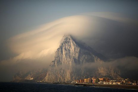 A cloud partially covers the tip of the Rock of the British territory of Gibraltar at sunrise from La Atunara port before Spanish fishermen A cloud partially covers the tip of the Rock of the British territory of Gibraltar at sunrise from La Atunara port before Spanish fishermen