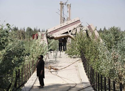 A fighter from the Islamist Syrian rebel group Jabhat al-Nusra stands on the historical Deir al-Zor Suspension Bridge, damaged by what activ A fighter from the Islamist Syrian rebel group Jabhat al-Nusra stands on the historical Deir al-Zor Suspension Bridge, damaged by what activ
