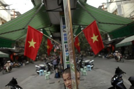 A Vietnamese boy is reflected in a mirror along a street decorated with national flags, in downtown Hanoi October 27, 2010. REUTERS/Damir Sa A Vietnamese boy is reflected in a mirror along a street decorated with national flags, in downtown Hanoi October 27, 2010. REUTERS/Damir Sa