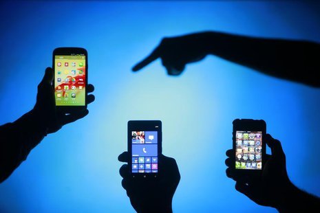 Men are silhouetted against a video screen as they pose with Samsung Galaxy S3, Nokia Lumia 820 and iPhone 4 smartphones (L-R) in this photo Men are silhouetted against a video screen as they pose with Samsung Galaxy S3, Nokia Lumia 820 and iPhone 4 smartphones (L-R) in this photo