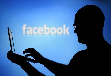 A man is silhouetted against a video screen with an Facebook logo as he poses with an Dell laptop in this photo illustration taken in the ce A man is silhouetted against a video screen with an Facebook logo as he poses with an Dell laptop in this photo illustration taken in the ce