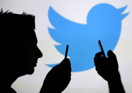 Men are silhouetted against a video screen with an Twitter logo as he poses with an Samsung S4 smartphone in this photo illustration taken i Men are silhouetted against a video screen with an Twitter logo as he poses with an Samsung S4 smartphone in this photo illustration taken i