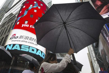 A woman holds an umbrella past the Nasdaq MarketSite in New York's Times Square, August 22, 2013. REUTERS/Lucas Jackson A woman holds an umbrella past the Nasdaq MarketSite in New York's Times Square, August 22, 2013. REUTERS/Lucas Jackson