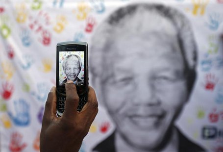 A well-wisher takes a picture using a cell phone of a banner with the image of former South African President Nelson Mandela, outside the Me A well-wisher takes a picture using a cell phone of a banner with the image of former South African President Nelson Mandela, outside the Me