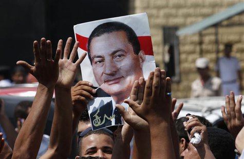 Supporters of former president Hosni Mubarak hold his poster to celebrate his release in front of the main gate of Tora prison, on the outsk Supporters of former president Hosni Mubarak hold his poster to celebrate his release in front of the main gate of Tora prison, on the outsk