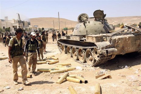 Free Syrian Army fighters inspect munitions and a tank that belonged to forces loyal to Syria's President Bashar al-Assad after they seized Free Syrian Army fighters inspect munitions and a tank that belonged to forces loyal to Syria's President Bashar al-Assad after they seized