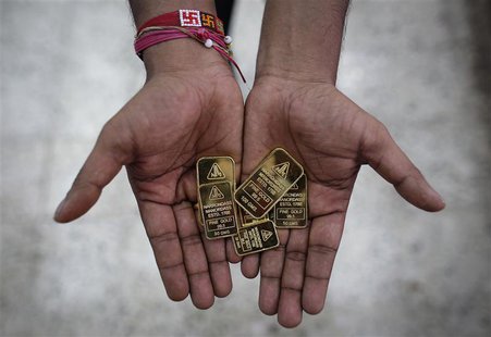 An employee poses with gold biscuits inside a jewellery showroom in Mumbai June 4, 2013. REUTERS/Danish Siddiqui An employee poses with gold biscuits inside a jewellery showroom in Mumbai June 4, 2013. REUTERS/Danish Siddiqui