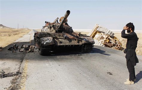A Free Syrian Army fighter stands near a damaged military tank that belonged to the forces loyal to Syria's President Bashar Al-Assad after A Free Syrian Army fighter stands near a damaged military tank that belonged to the forces loyal to Syria's President Bashar Al-Assad after