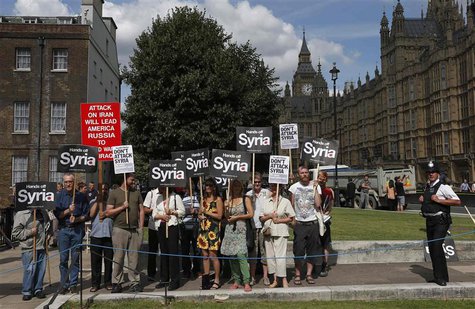 Demonstrators hold placards outside the Houses of Parliament in London August 29, 2013. Britain's parliament has been recalled to vote on ho Demonstrators hold placards outside the Houses of Parliament in London August 29, 2013. Britain's parliament has been recalled to vote on ho