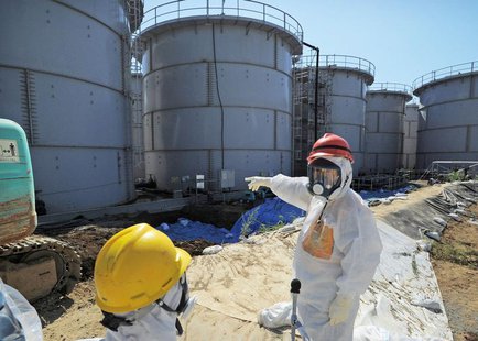 Japan's Economy, Trade and Industry Minister Toshimitsu Motegi (R), wearing a protective suit and a mask, inspects contaminated water tanks Japan's Economy, Trade and Industry Minister Toshimitsu Motegi (R), wearing a protective suit and a mask, inspects contaminated water tanks