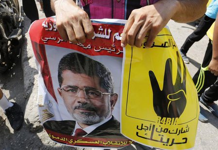 Supporters of ousted Egyptian president Mohamed Mursi hold his picture and a poster (R) showing the "Rabaa" or "four" gesture, in reference Supporters of ousted Egyptian president Mohamed Mursi hold his picture and a poster (R) showing the "Rabaa" or "four" gesture, in reference